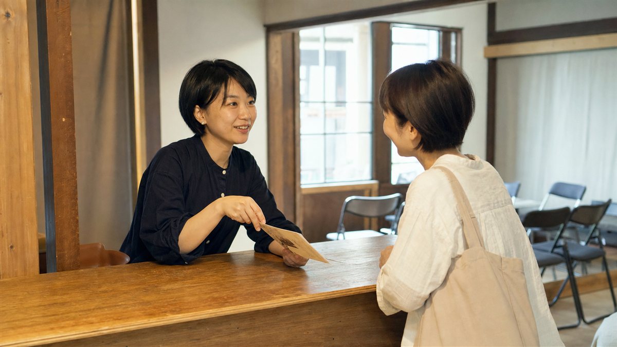上映会の受付で来場者がスタッフに質問している場面