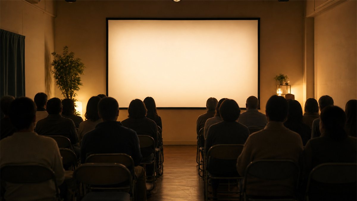 小さな上映会場でスクリーンの光を静かに見つめる観客の後ろ姿